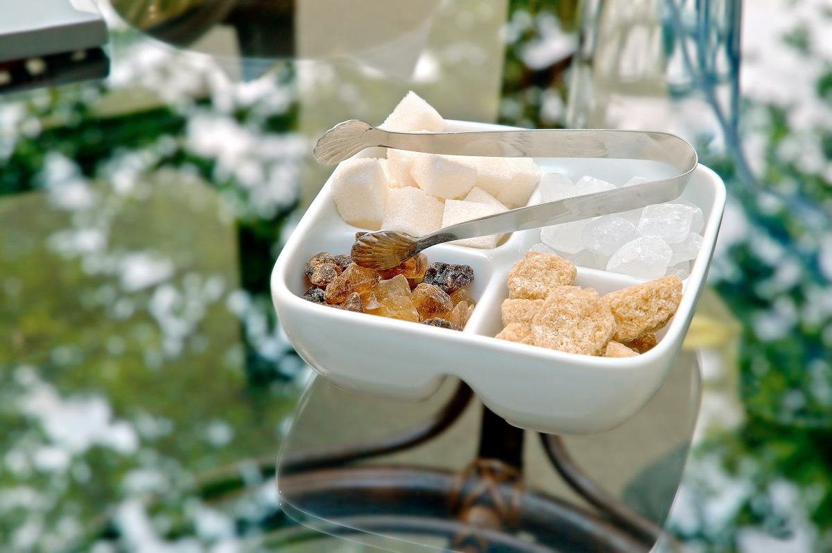 мъж прибавя захар към своята чаша с кафе