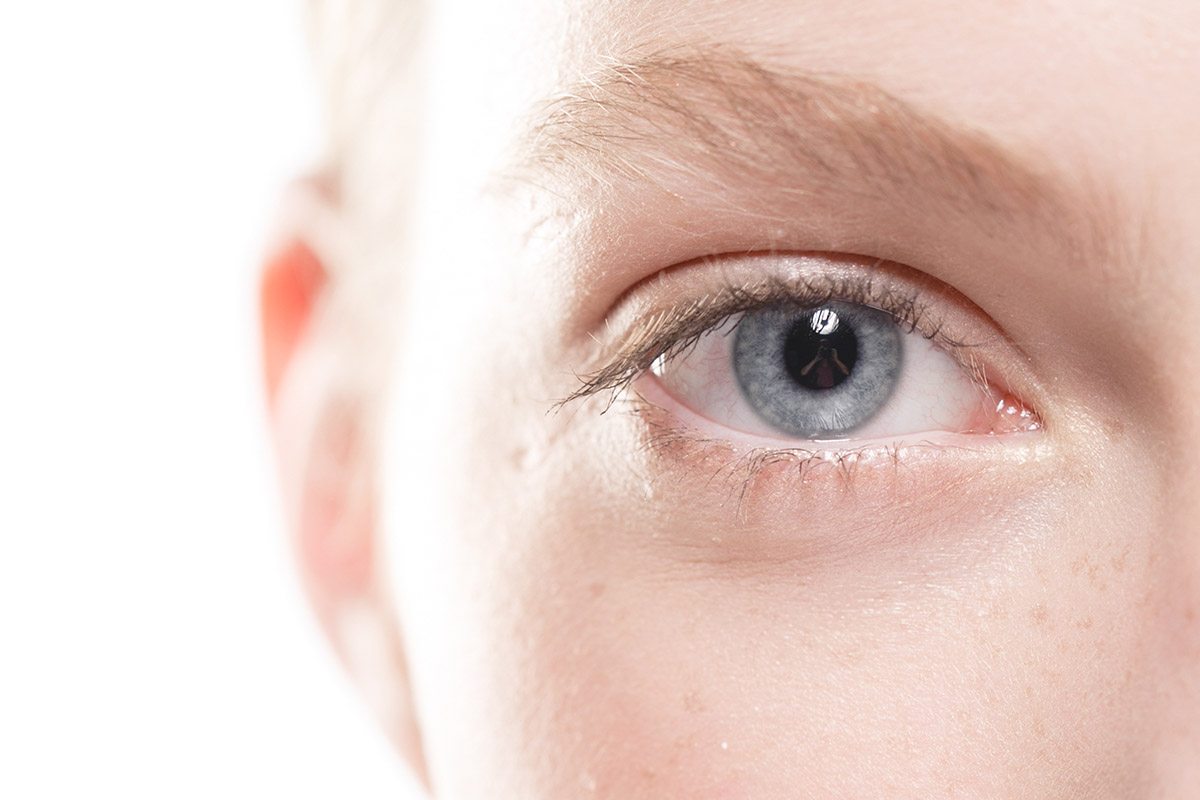 Мъж с присвити очи държи очила